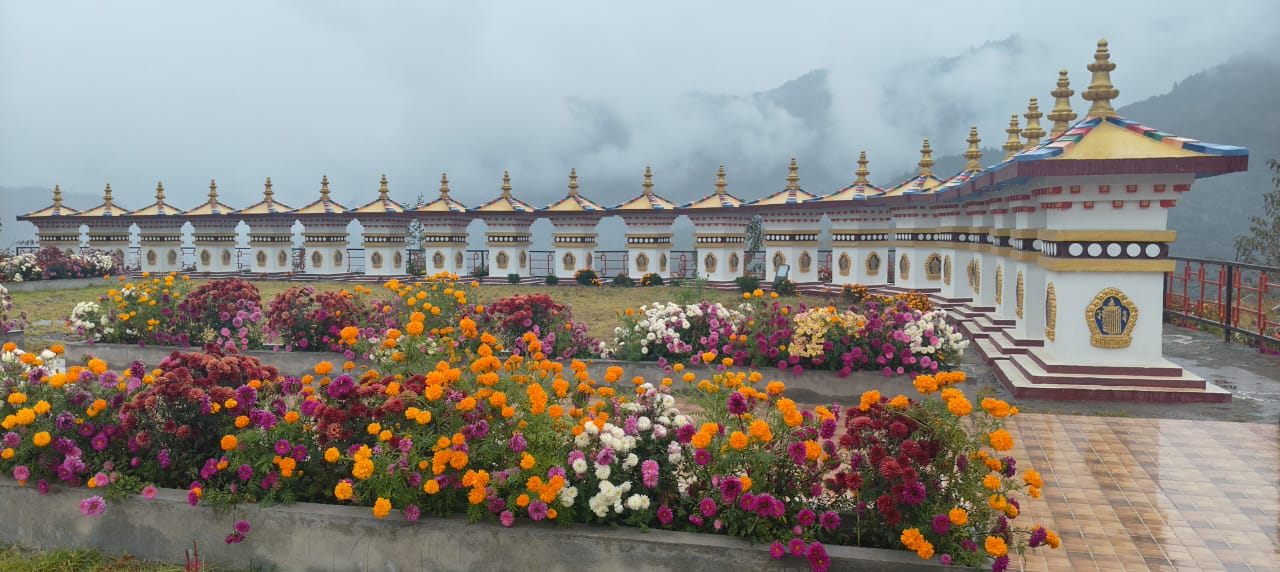 Rows of white and gold stupas at Mandala Top above Dirang with marigold beds and cloud below