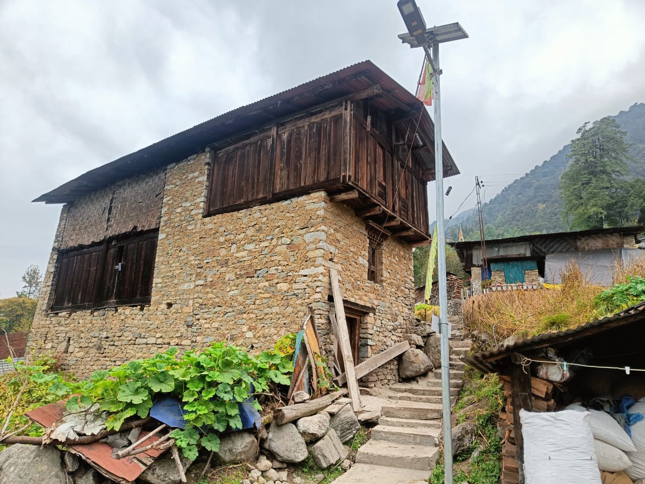 A two-storey stone and timber house on a stepped lane in the fortified Monpa village of Thembang