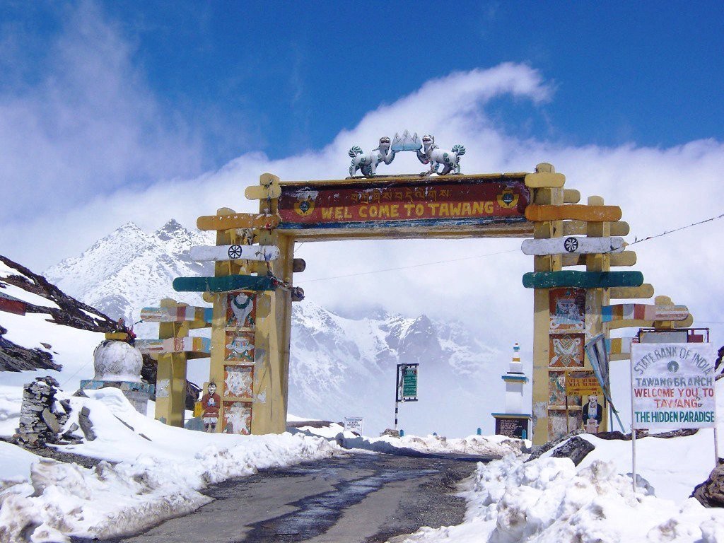 The painted Welcome to Tawang gateway with snow peaks behind it