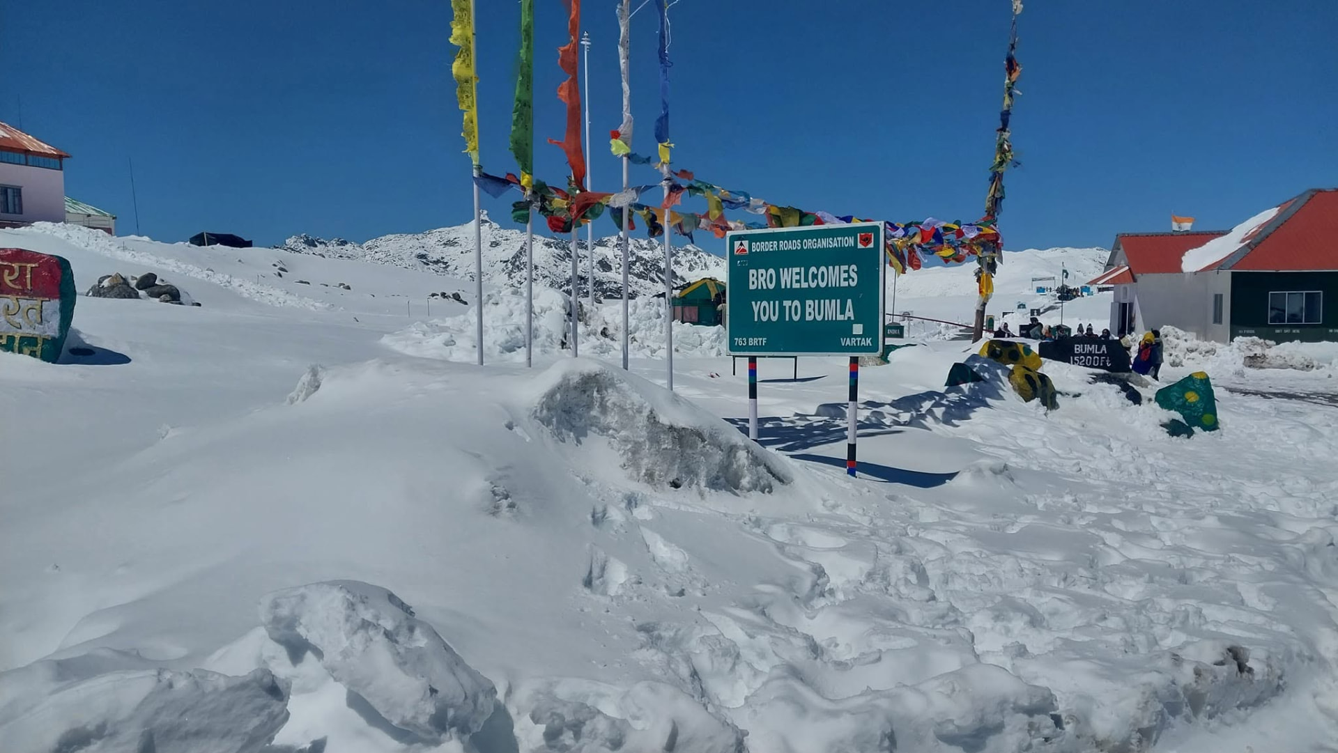 Border Roads Organisation signboard welcoming visitors to Bumla Pass, surrounded by snow and prayer flags