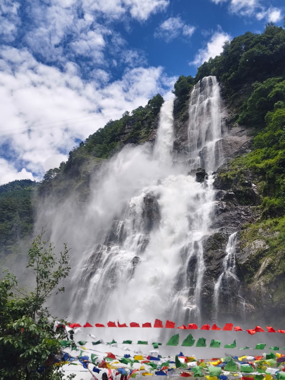 Nuranang Falls dropping down a rock face with prayer flags strung in the foreground